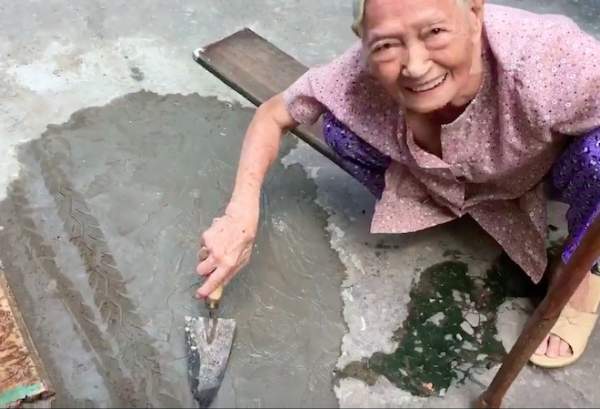 Xôn xao clip cụ bà ngoài 80 tuổi tự trộn xi-măng “vá” đường ở TP.HCM